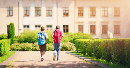 Children with rucksacks standing in the park near schoolの写真素材