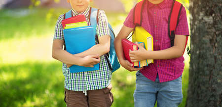 Children with rucksacks standing in the park near schoolの写真素材
