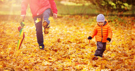 Child standing with umbrella in beautiful autumnal dayの写真素材