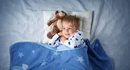 six years old child sleeping in bed with alarm clockの写真素材