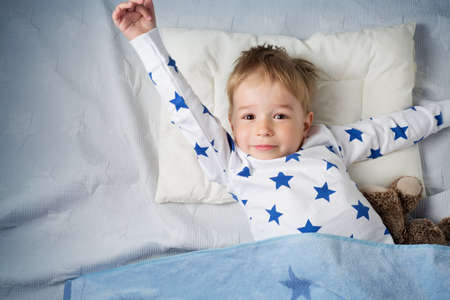 six years old child sleeping in bed with alarm clockの写真素材