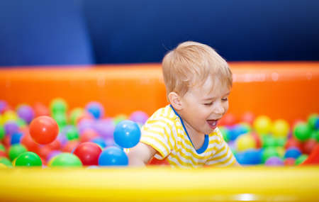 Little boy playing on playroom with ballpitの写真素材