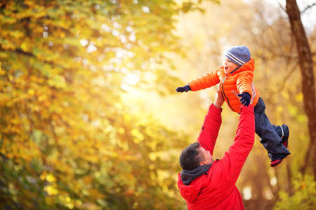 Father playing with son on sunny day in autumnの写真素材