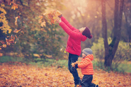 children throwing leaves in beautiful autumnal dayの写真素材