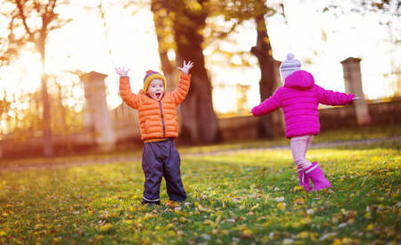 children throwing leaves in beautiful autumnal dayの写真素材