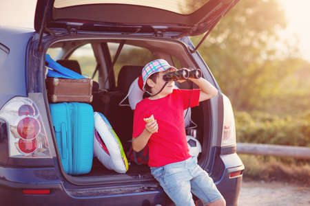 child sitting in car filled with traveling accessoriesの写真素材