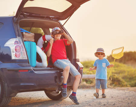 child sitting in car filled with traveling accessoriesの写真素材