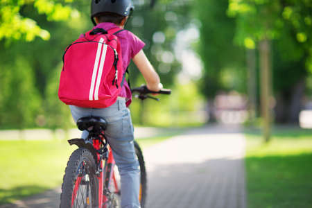 Child with rucksack riding on bike in the park near schoolの写真素材