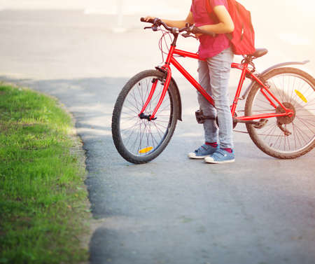 Child with rucksack riding on bike in the park near schoolの写真素材