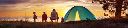 Family resting with tent in nature at sunsetの写真素材