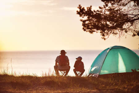 Family resting with tent in nature at sunsetの写真素材