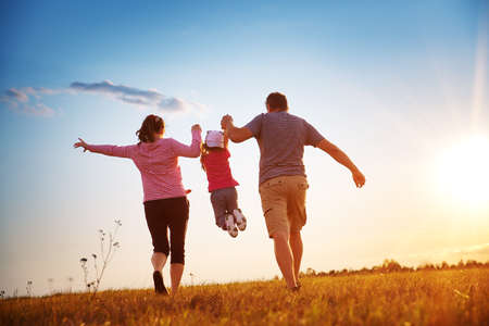 girl with mother and father holding hands on the natureの写真素材