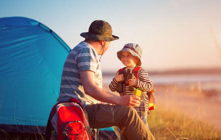 Family resting with tent in nature at sunsetの写真素材