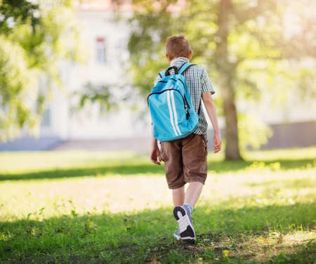 Boy with rucksack infront of a school buildingの写真素材