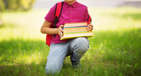 Child with rucksack sitting in the park near schoolの写真素材