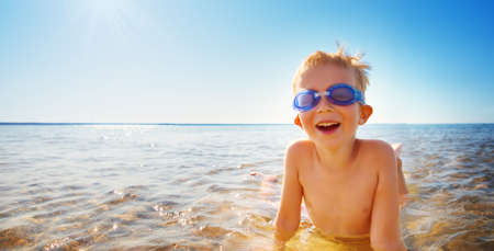 four years old boy playing at the beach with swimming glassesの写真素材