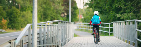 Child with rucksack riding on bike in the park near schoolの写真素材