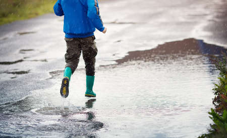 Child walking in wellies in puddle on rainy weatherの写真素材