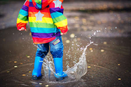 Child walking in wellies in puddle on rainy weatherの写真素材