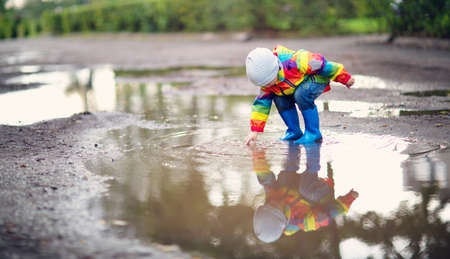 Child walking in wellies in puddle on rainy weatherの写真素材