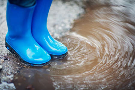 Child walking in wellies in puddle on rainy weatherの写真素材