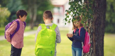 Children with rucksacks standing in the park near schoolの写真素材