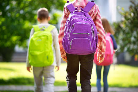 Children with rucksacks standing in the park near schoolの写真素材