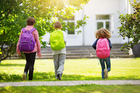 Children with rucksacks standing in the park near schoolの写真素材