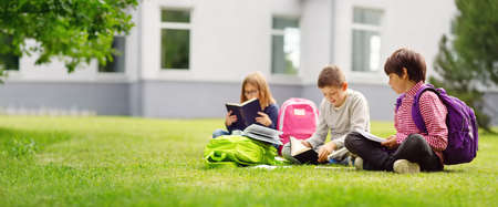 Children with rucksacks standing in the park near schoolの写真素材