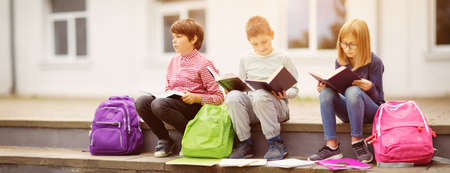 Children with rucksacks standing in the park near schoolの写真素材