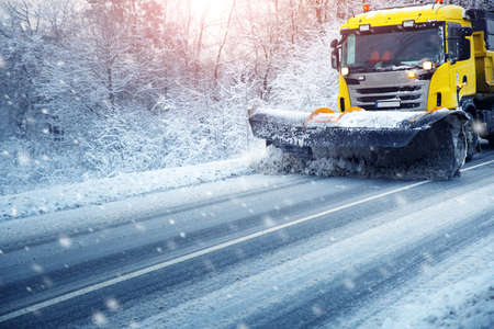 Truck cleaning on winter road covered with snowの写真素材