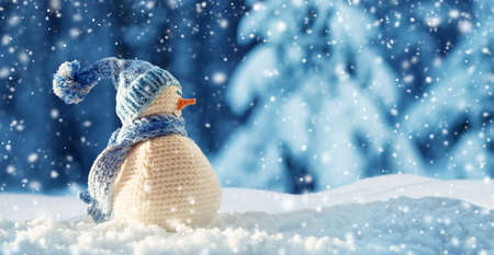 little snowman on soft snow on blue backgroundの写真素材