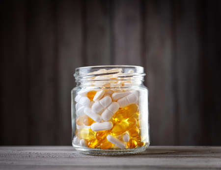 Pills in a jar on wooden backgroundの写真素材