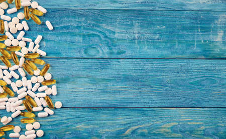 Pills spilled on blue wooden backgroundの写真素材