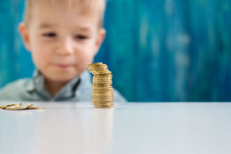 three years old child sitting st the table with money coinsの写真素材