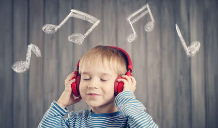 little boy on wooden background with red headphonesの写真素材