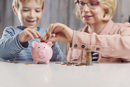 three years old child sitting st the table with money and a piggybankの写真素材