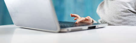 happy five years old child sitting with a laptop at tableの写真素材