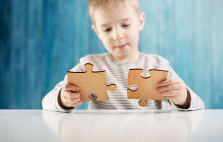 Little child holding puzzle pieces and trying to solve itの写真素材