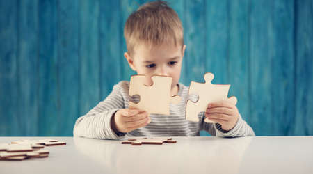 Little child holding puzzle pieces and trying to solve itの写真素材