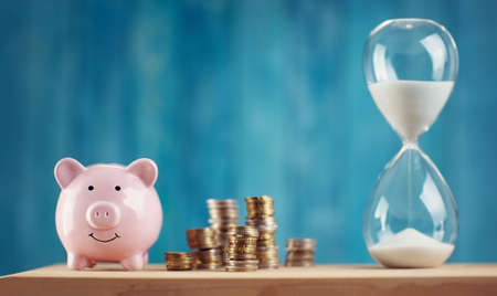 piggy bank with stacked coins and hourglassの写真素材