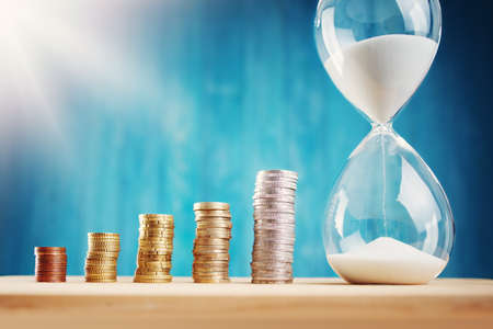 Clock with stacked coins. Pig with money savings and hourglass on blue background