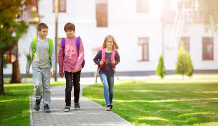 Children with rucksacks standing in the park near schoolの写真素材