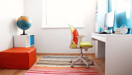 Colourful children rooom with white walls and furniture. Desk at home interior with a windowの写真素材