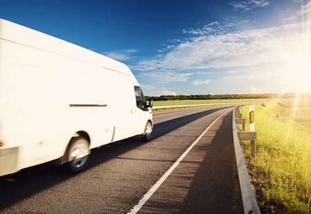 asphalt road on dandelion field with a small truckの写真素材