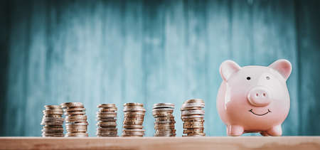 piggy bank with stacked coins on blue backgroundの写真素材