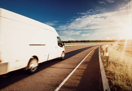 asphalt road on dandelion field with a small truckの写真素材