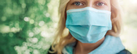 young woman in medical face protection mask outdoors in natureの写真素材