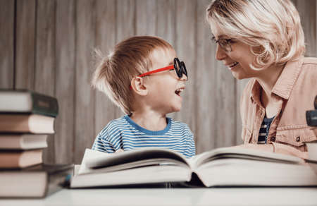 five years old child reading a book at home with motherの写真素材