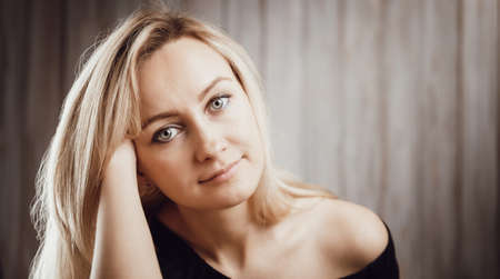 Happy beautiful young blond woman portrait with wooden backgroundの写真素材